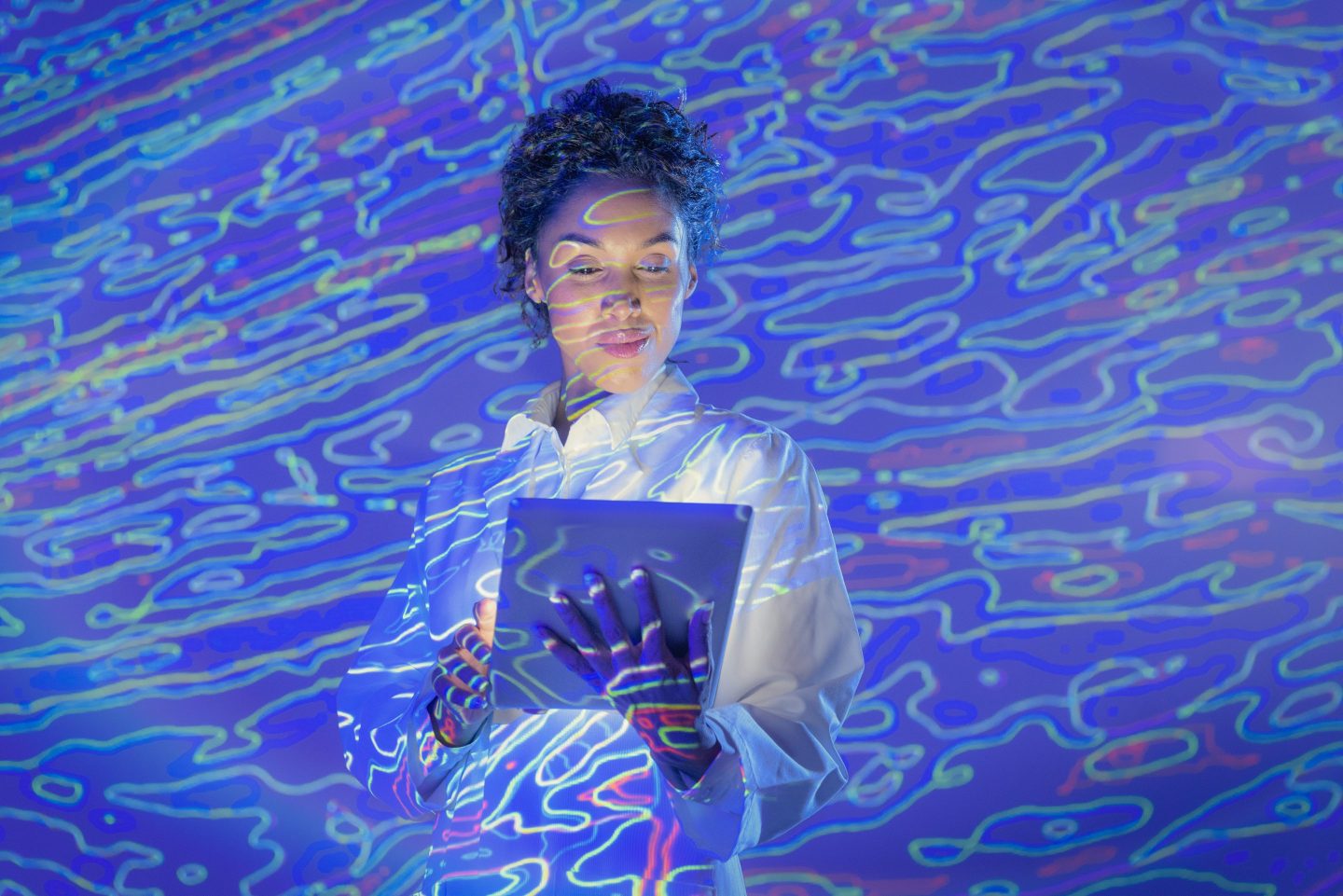A woman looking at a screen with an overlay of fluid imagery to show change and flexibility.
