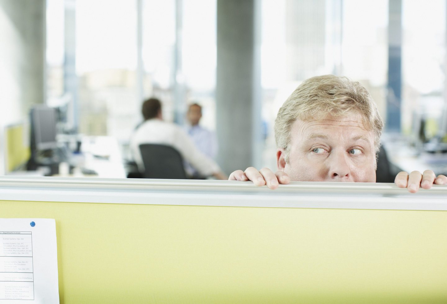 office worker peering over a cubicle wall