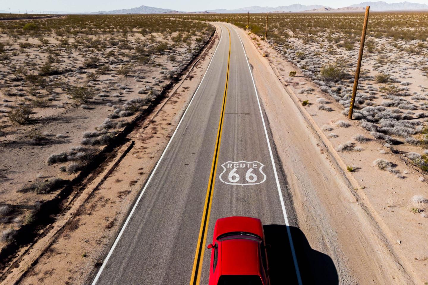 Drone view of American car driving in a straight road at the California desert