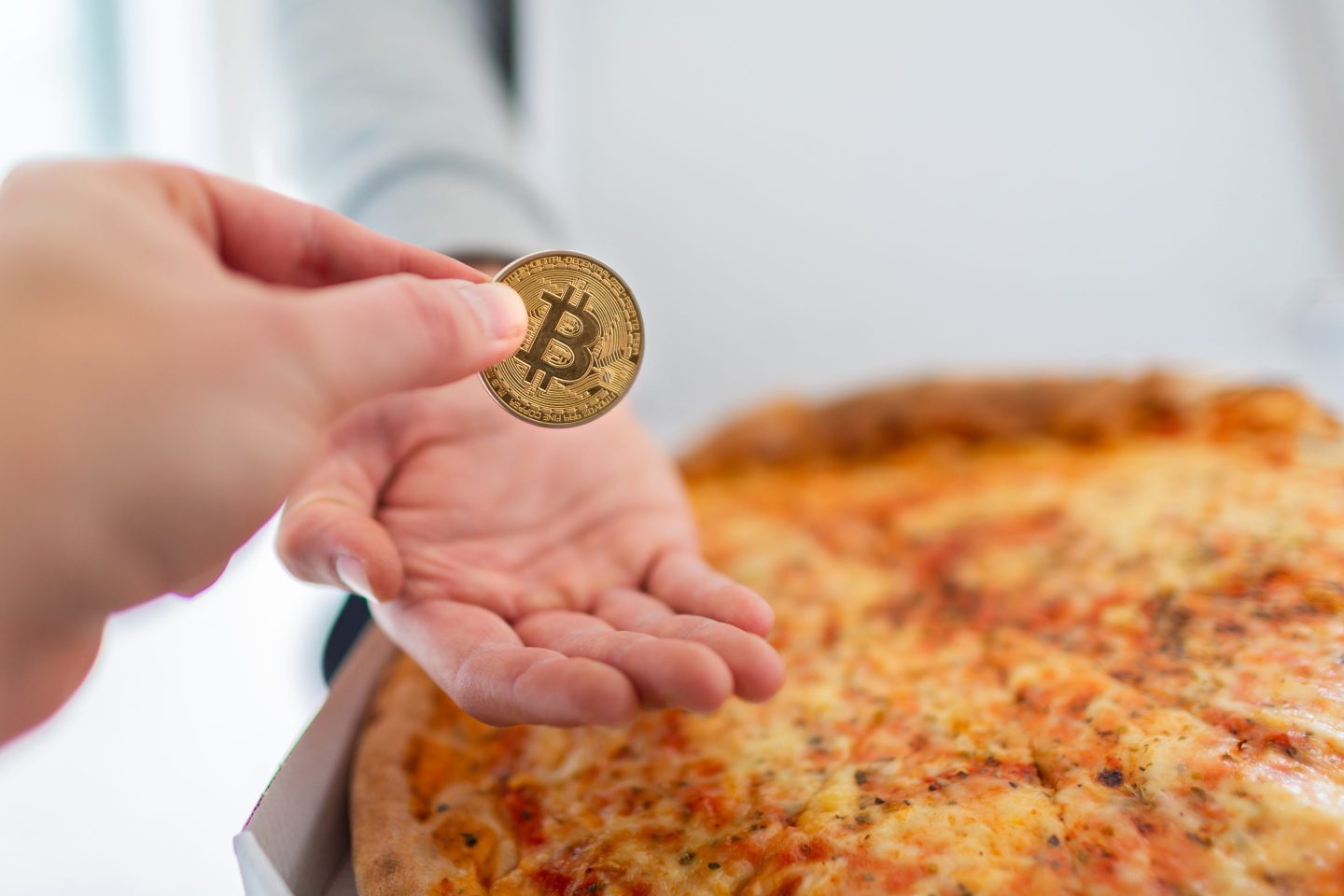 A man putting a bitcoin into another man's hand in exchange for a pizza pie