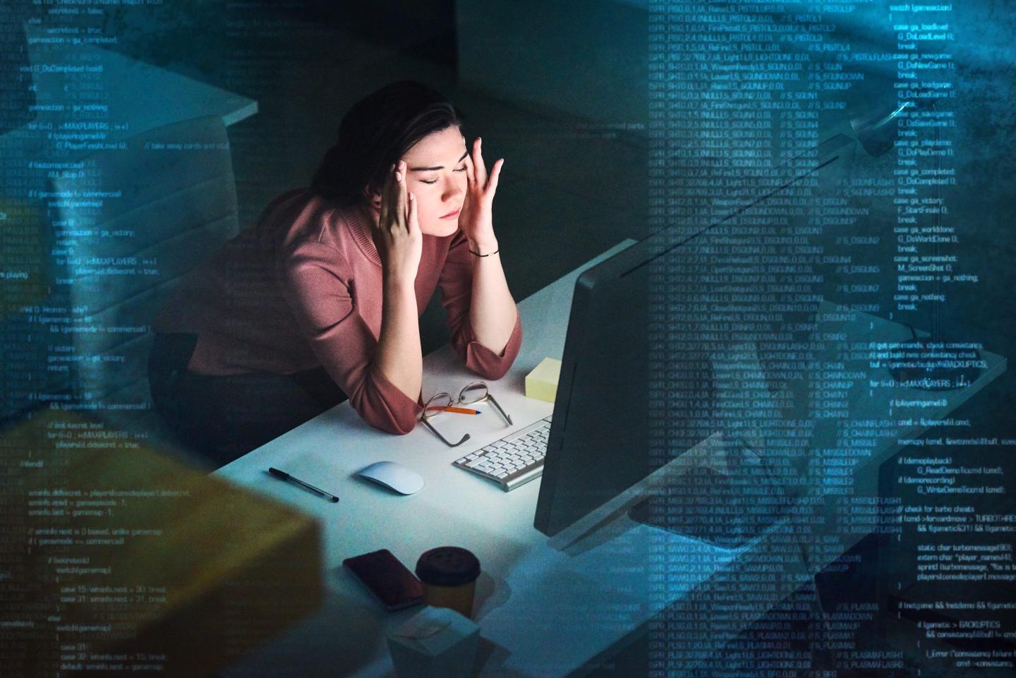 young programmer working on computer code at night and looking stressed
