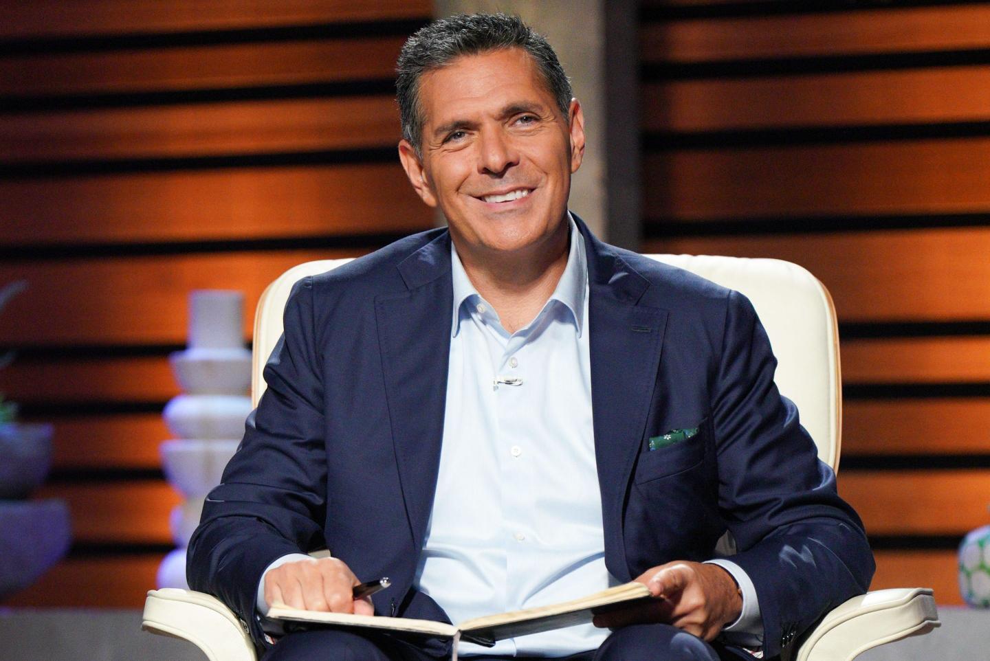 Daniel Lubetzky sits with a book in his hand on the set of Shark Tank