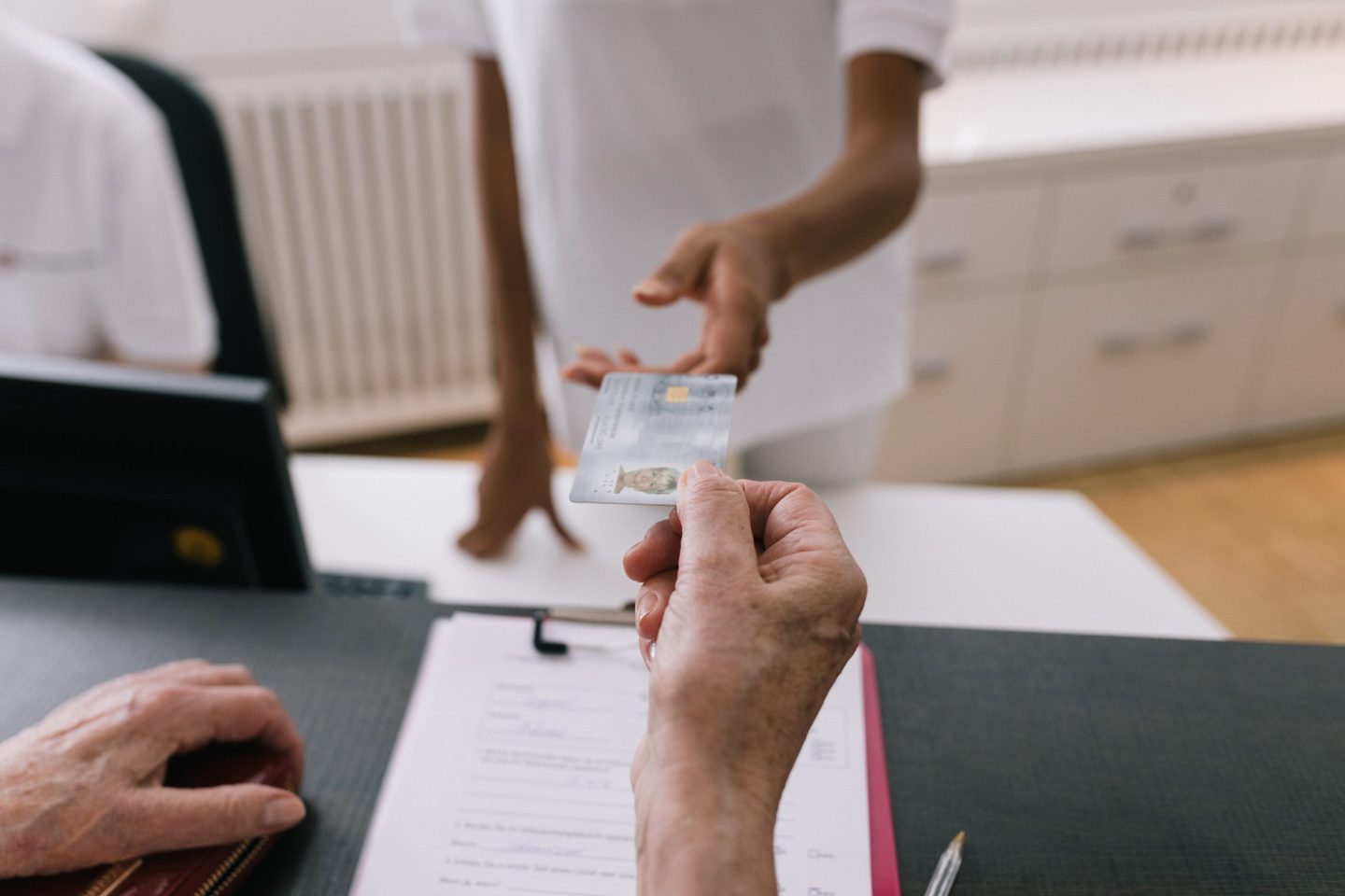 A woman handing over her medical insurance card to the receptionist at an MRI clinic reception in order to pay for her scan and follow up treatment.