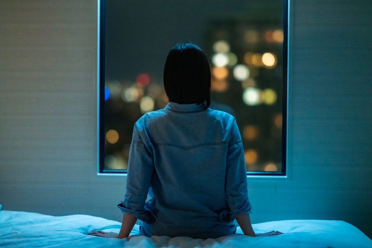 Woman sitting up on her bed at night