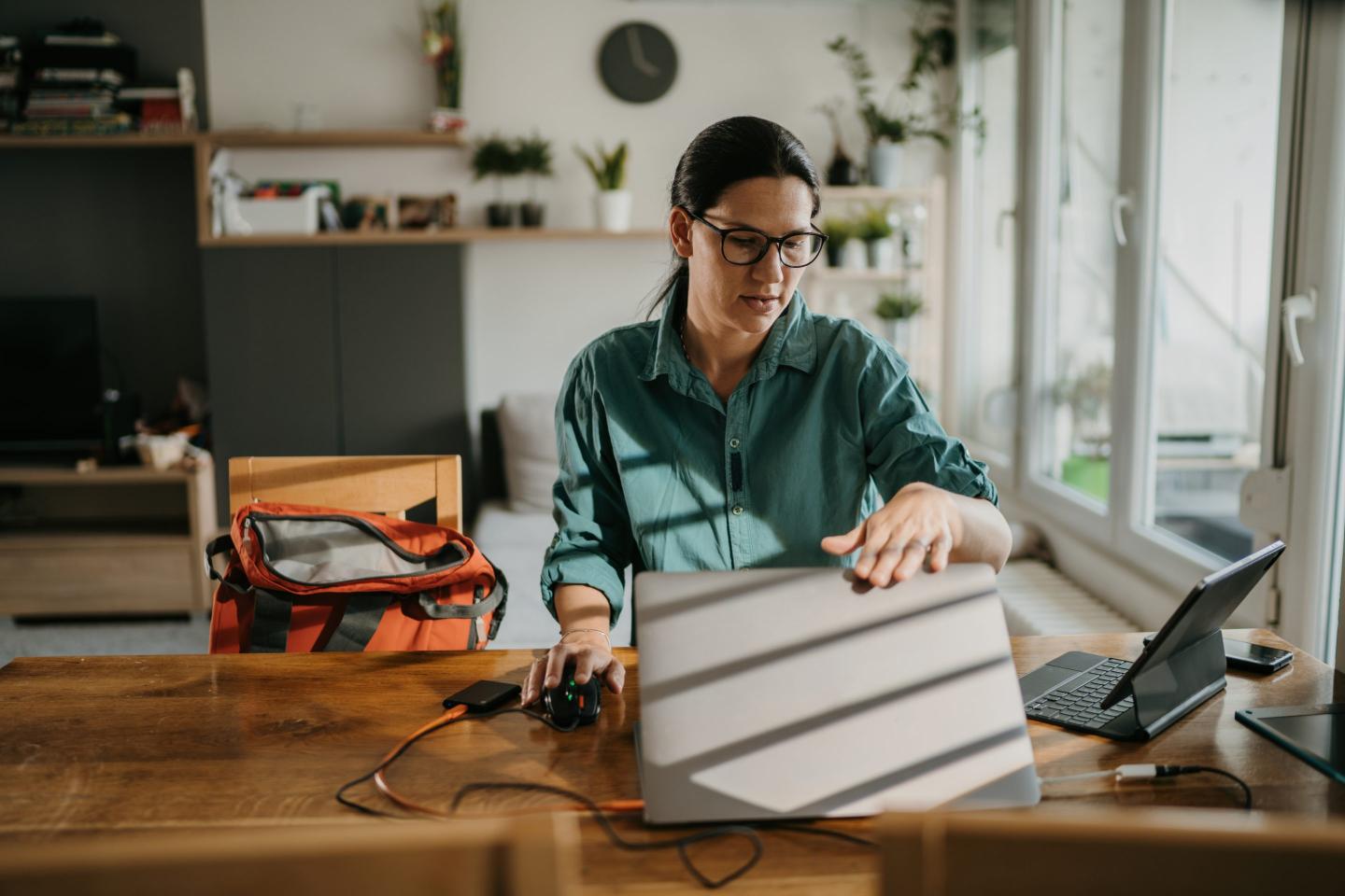 A woman sitting at a desk closes her laptop.