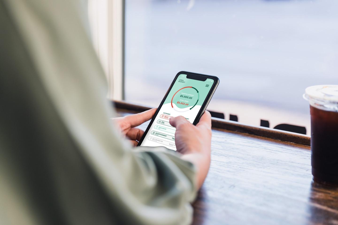 A person looking at their banking app in a coffee shop.