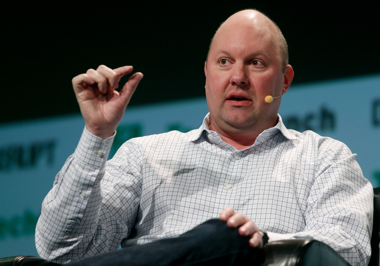 Marc Andreessen speaking on stage holding a hand up.