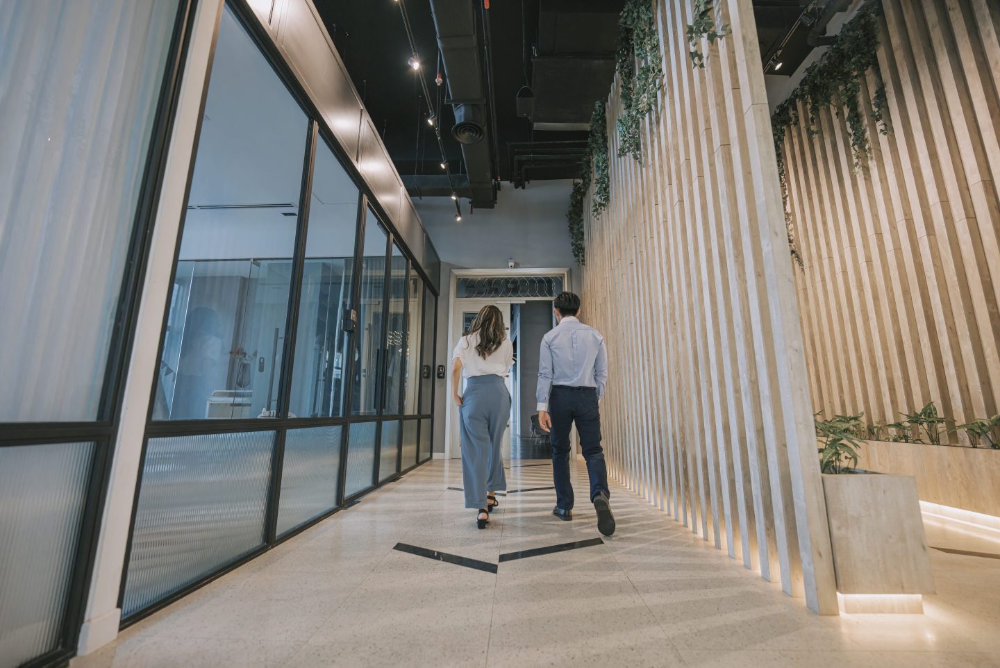Two colleagues walking in corridor on the way out of an office.