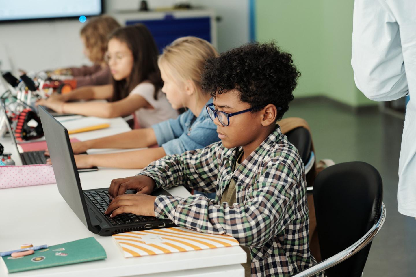 Students work at laptops in a classroom