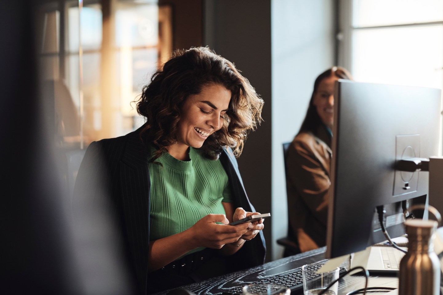 Women uses her phone at a work desk