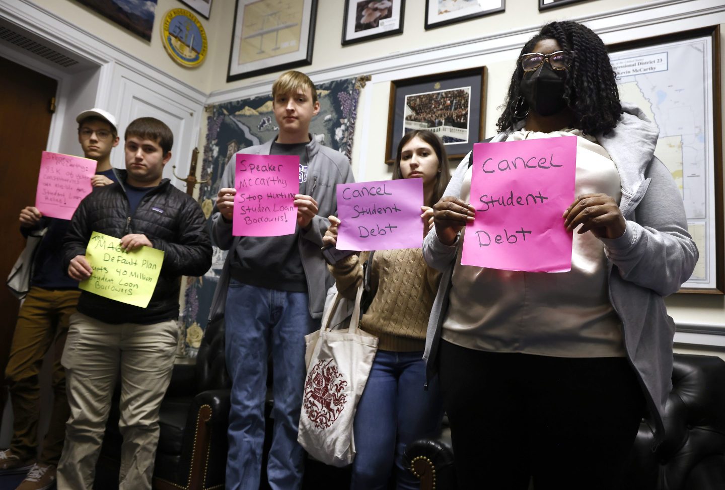 Students hold up signs that say "Cancel Student Debt" and similar messages during a protest in then-House Speaker Kevin McCarthy's office.