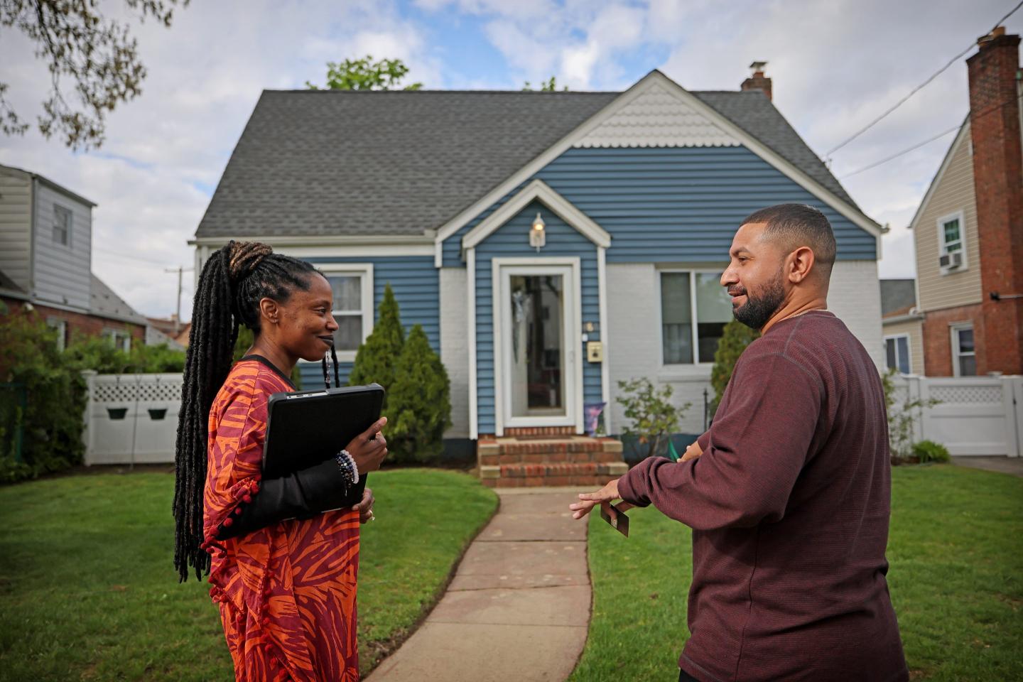 Real estate broker Susan Chen speaks with potential home buyer Hector Camacho outside of a open house in Valley Stream, New York, on May 4, 2023.