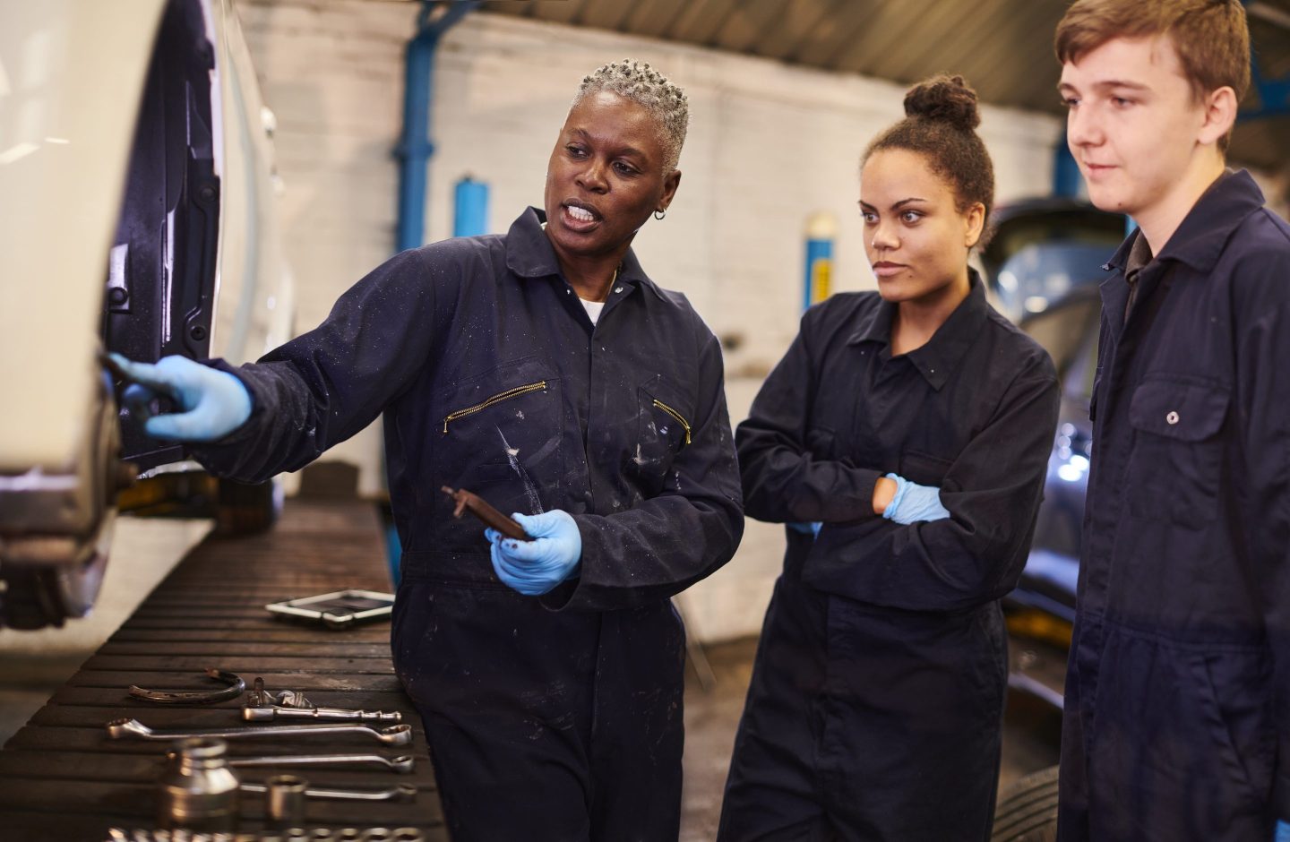 Auto worker with apprentices in factory