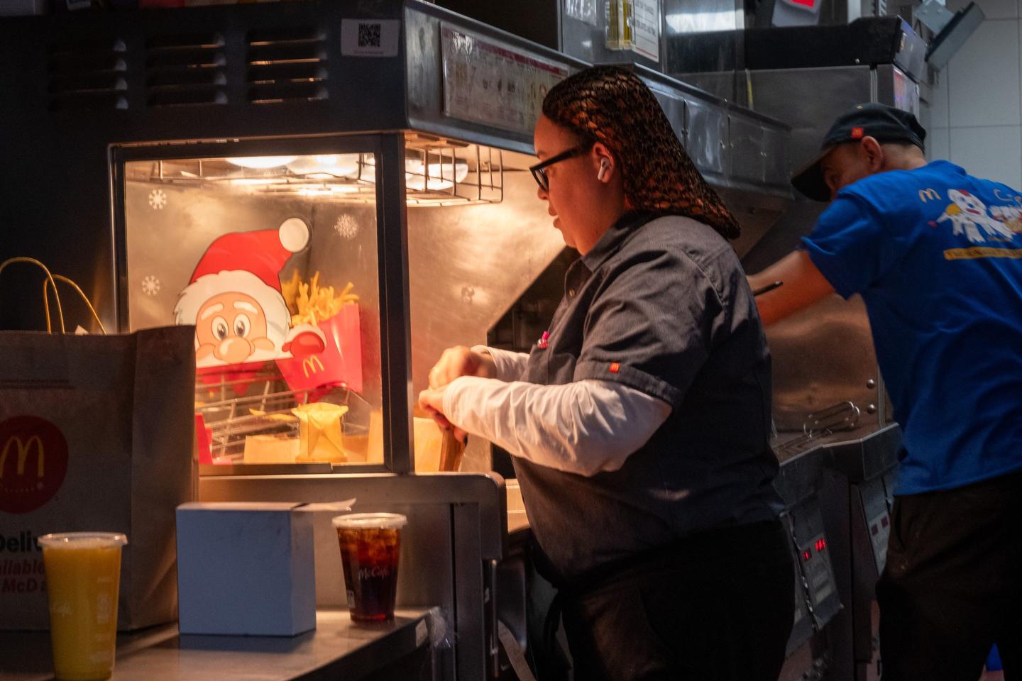 A McDonald's worker scoops fries into a container.