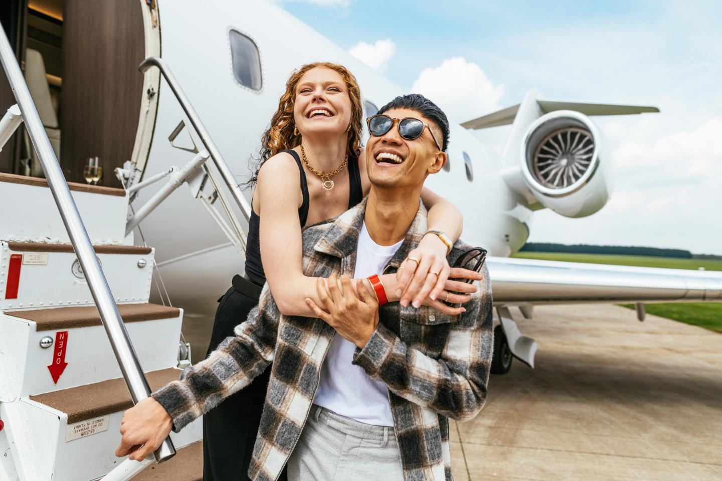 Young rich couple exits plane.