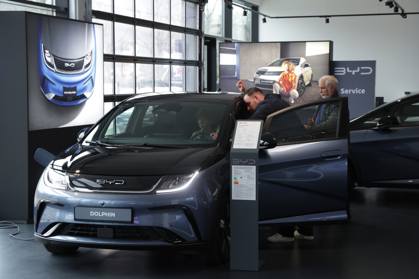 Potential customers inspect a new BYD vehicle on a showroom floor.