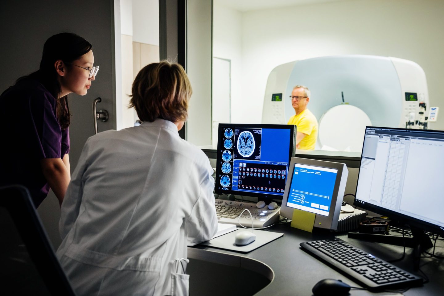 Doctor looking at a screen as a patient gets ready for CT scan