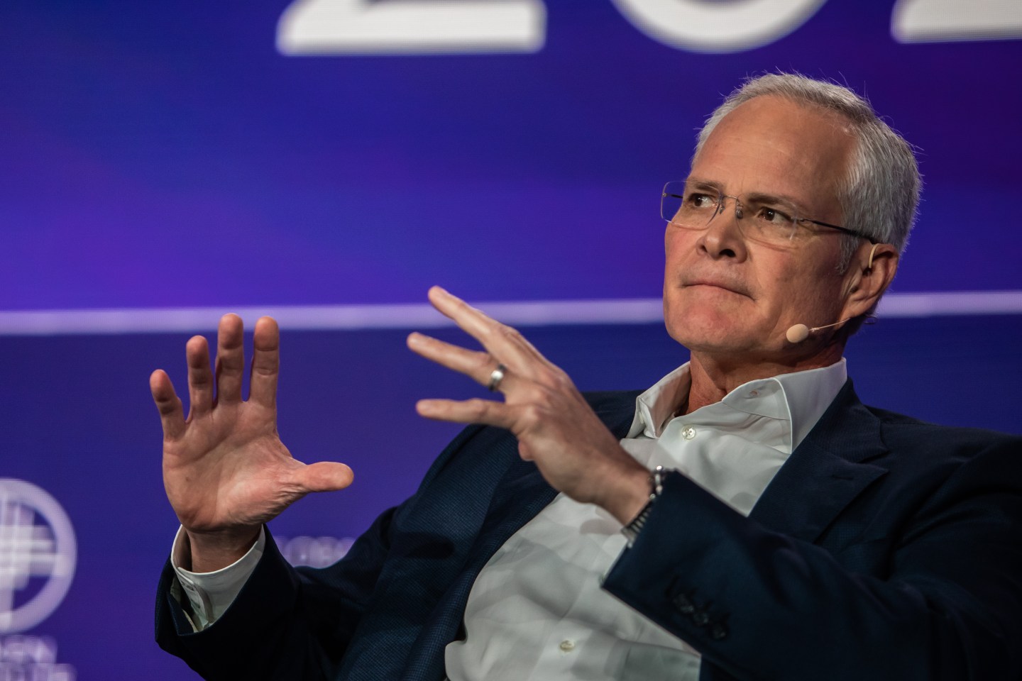 Exxon Mobil chairman and CEO Darren Woods talks while seated at a conference.