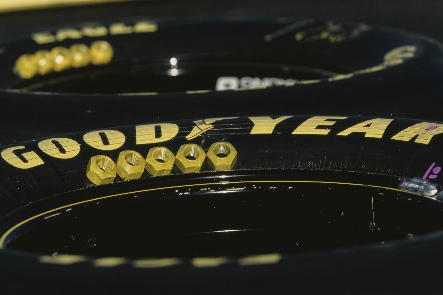 A detailed view of lug nuts laid out on Goodyear Eagle racing tyres along pit road.