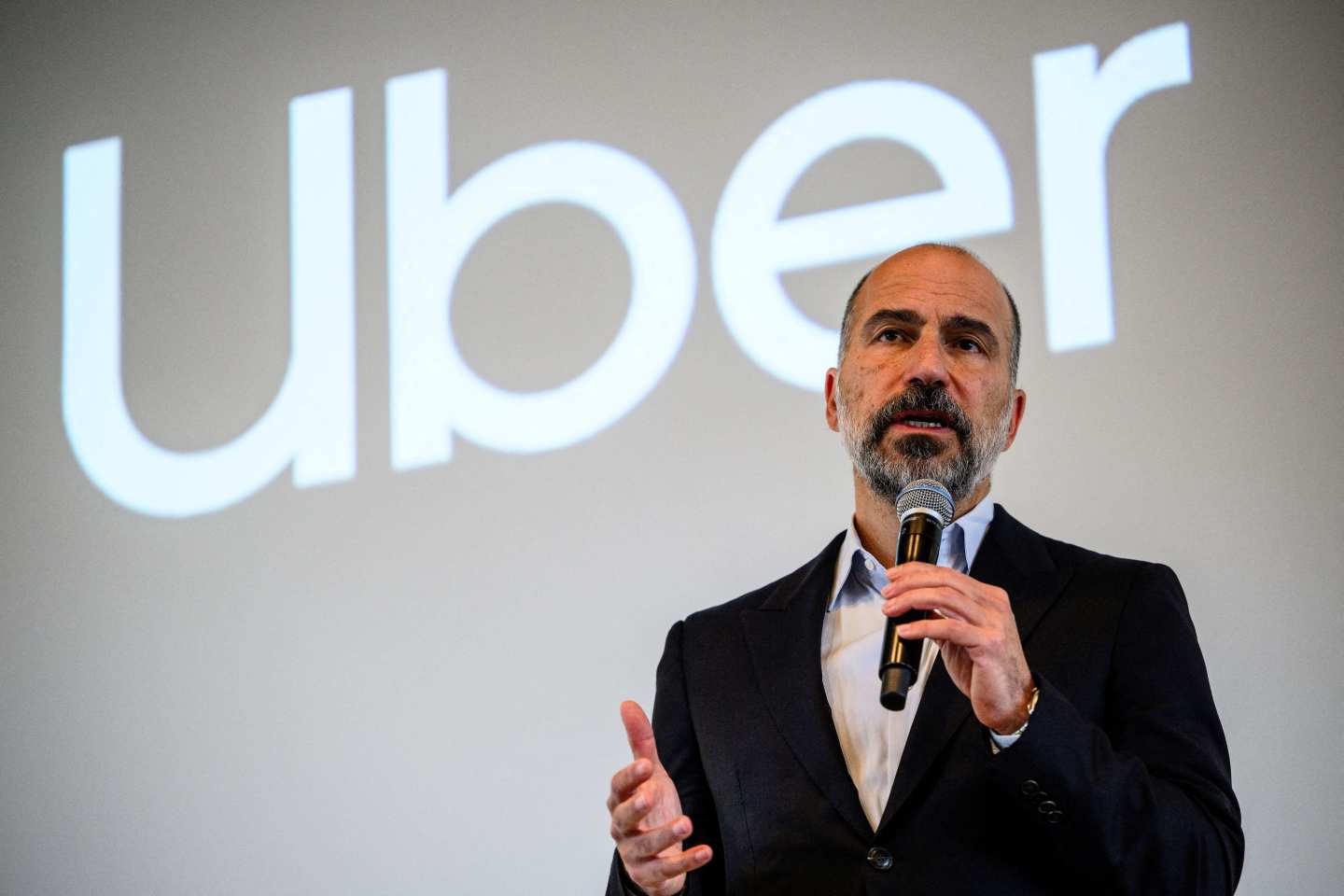 Uber CEO talking on stage with the company's logo projected behind him