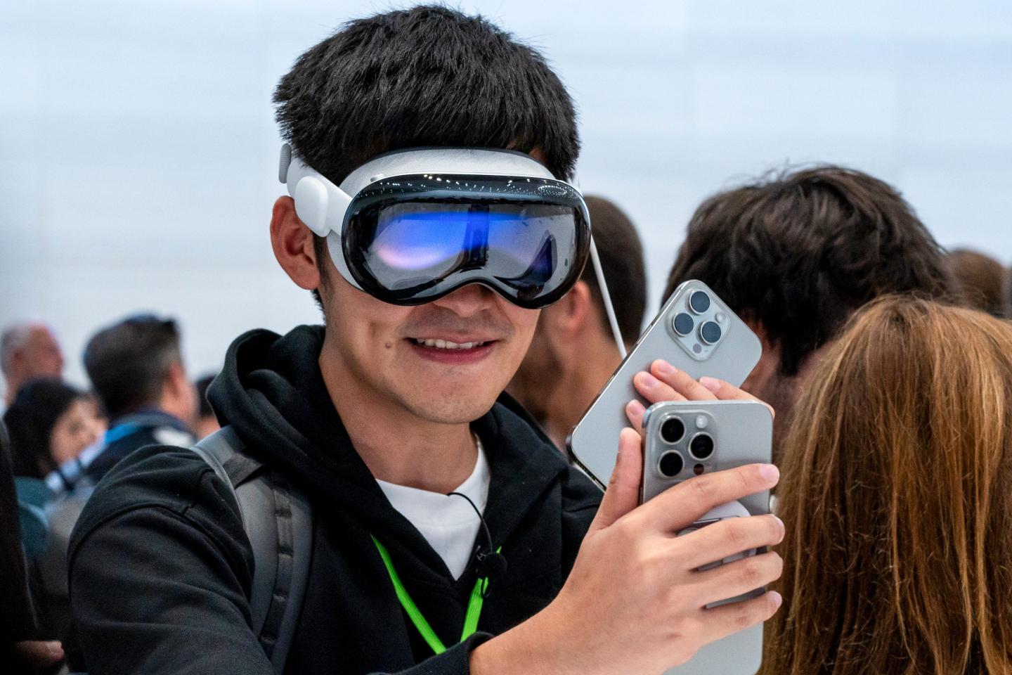 A man wears Apple Vision Pro while looking at iPhones