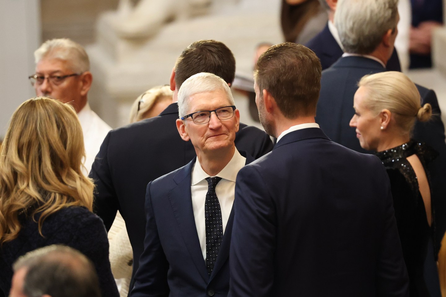 Apple CEO Tim Cook talking to a man at Trump's inauguration.