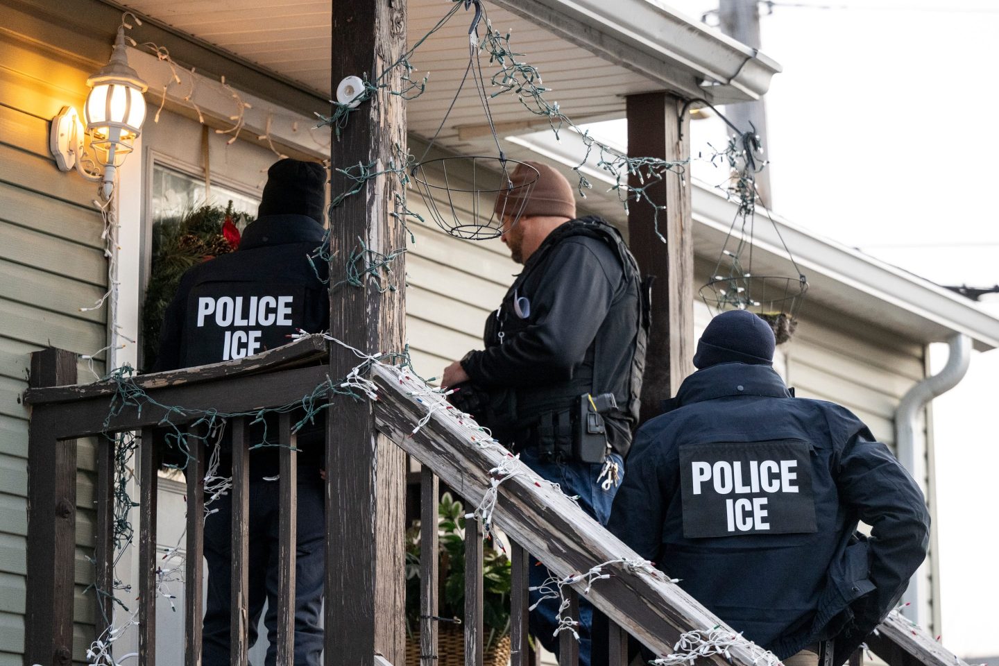 ICE agents stand outside a house to arrest an immigrant