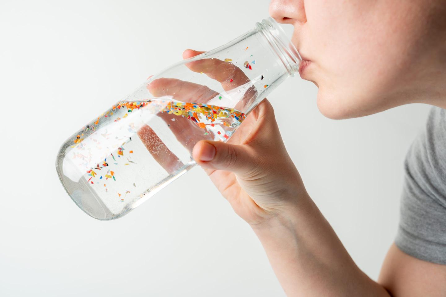 Close-up of person drinking water from transparent glass bottle