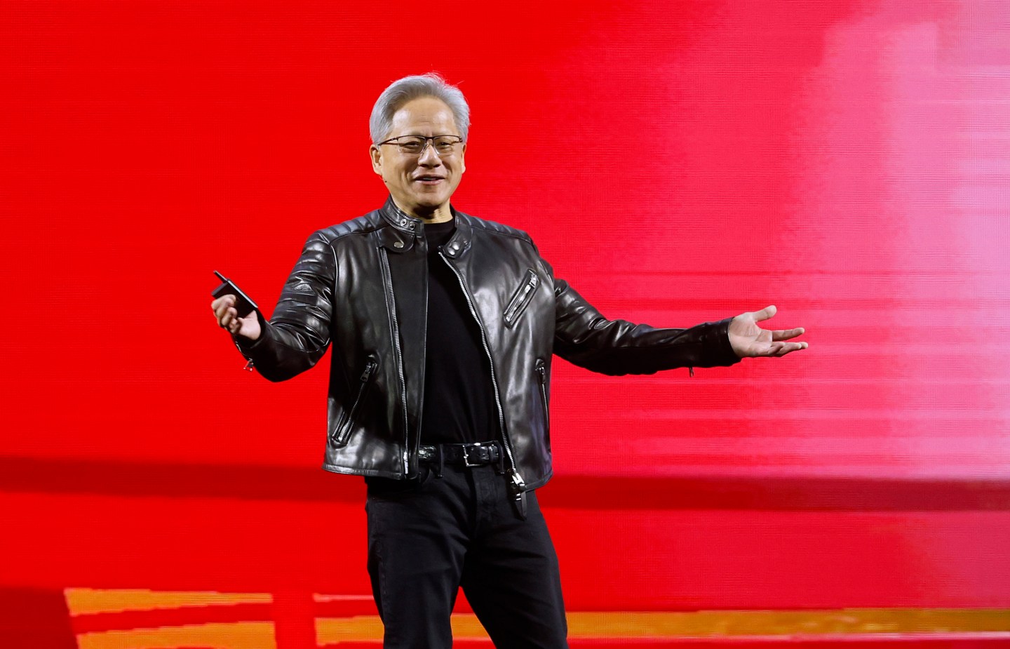 Jensen Huang standing on a stage with a red background