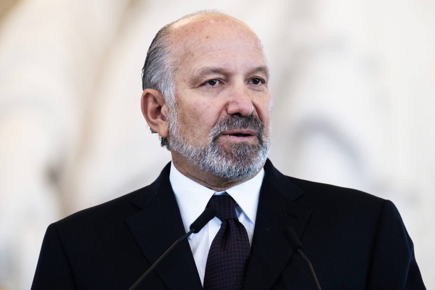 Howard Lutnick, wearing a black suit, speaks into a microphone.