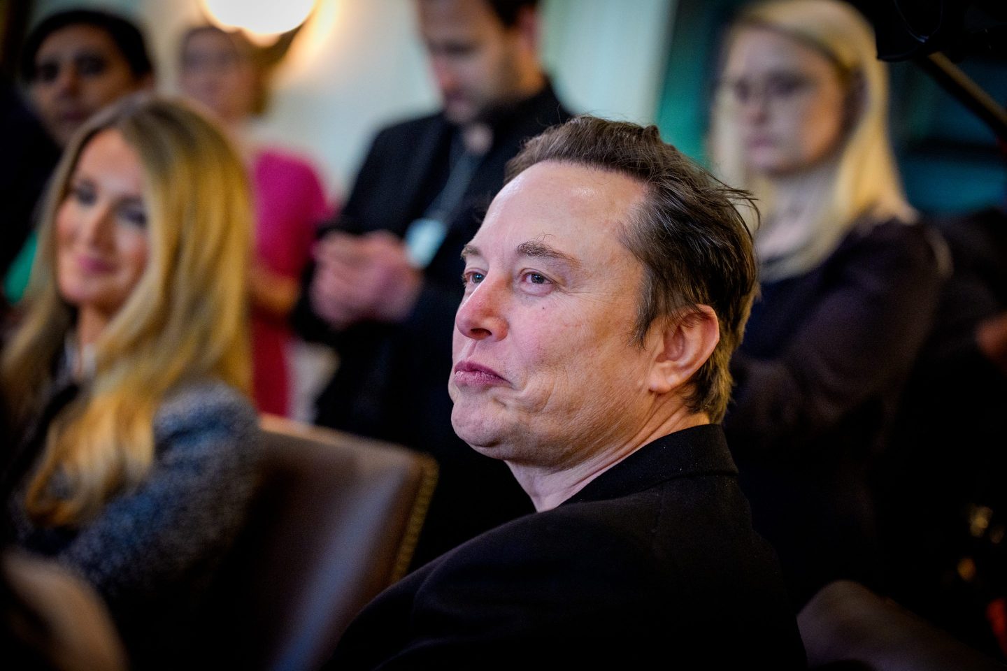 Elon Musk smirks and looks to his right.