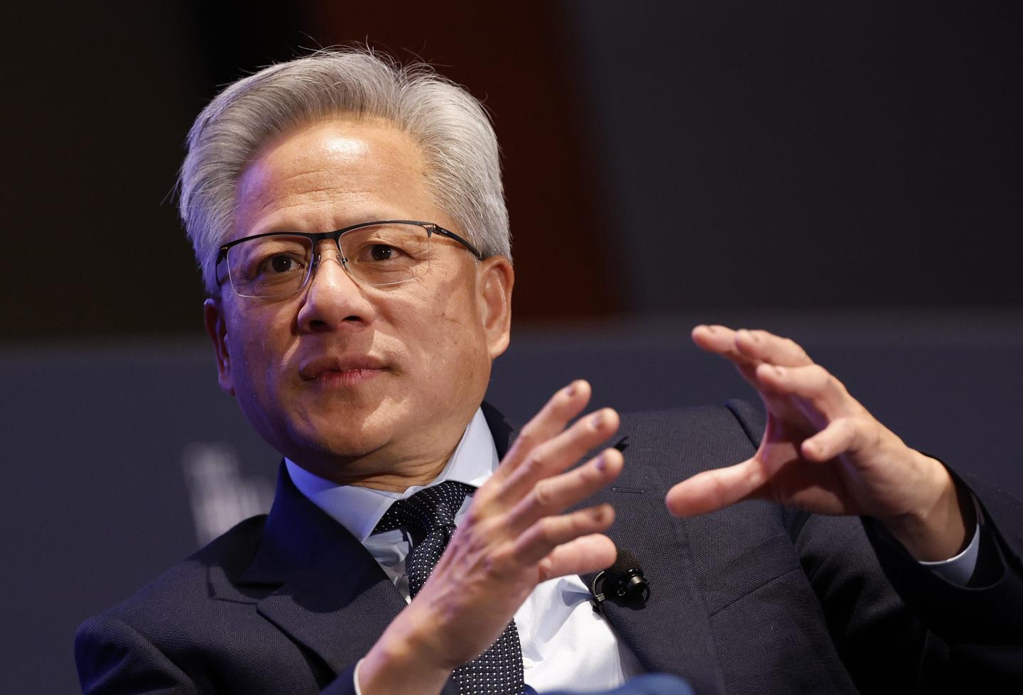 Jensen Huang gestures wearing a suit and tie