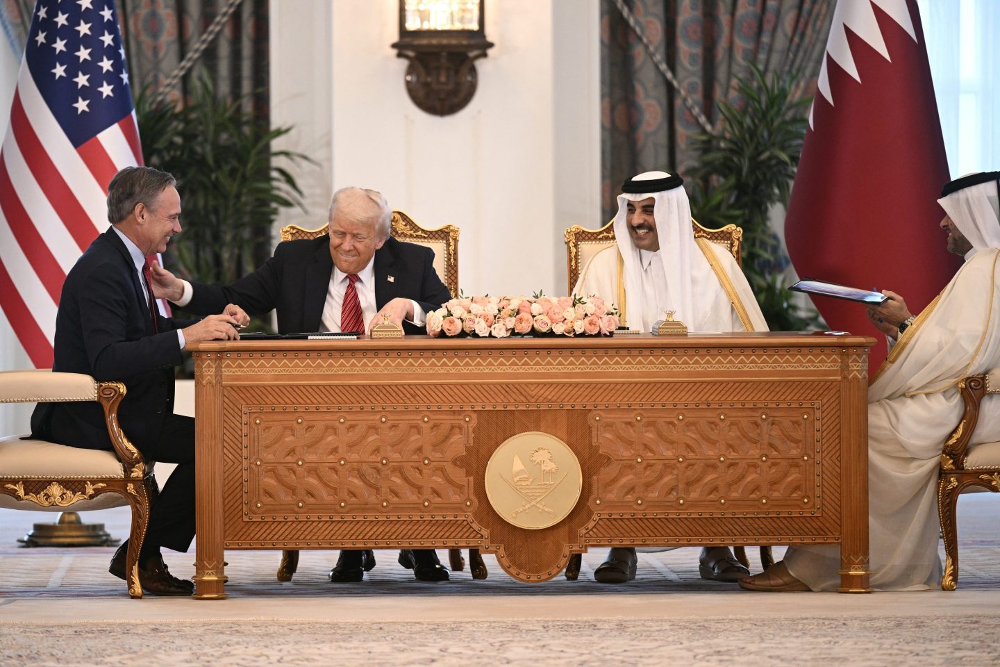 Boeing CEO Kelly Ortberg sits to the left of US President Donal Trump and Qatar's Emir Sheikh Tamim bin Hamad al-Thani (R) during a business deal signing ceremony at the Royal Palace in Doha, on May 14, 2025.