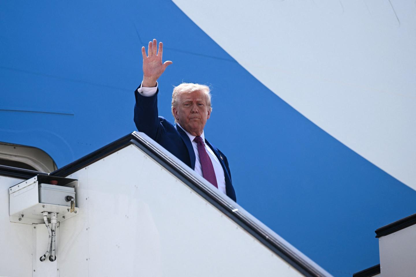 President Donald Trump waves goodbye aboard Air Force One