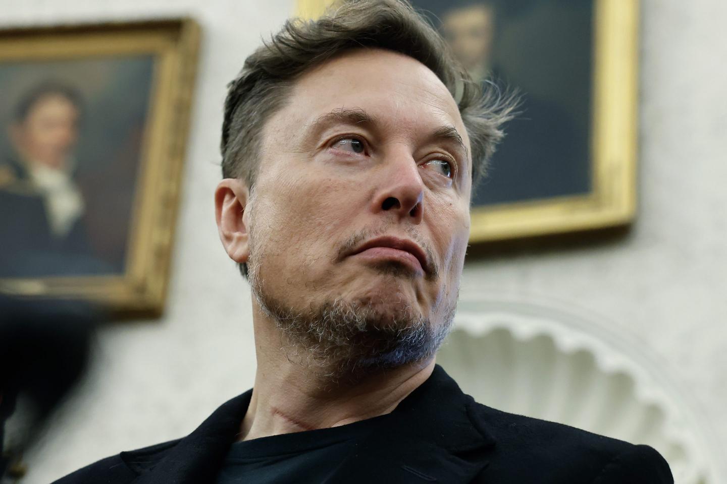 Elon Musk listens as reporters ask U.S. President Donald Trump and South Africa President Cyril Ramaphosa questions during a press availability in the Oval Office at the White House on May 21, 2025 in Washington, DC.