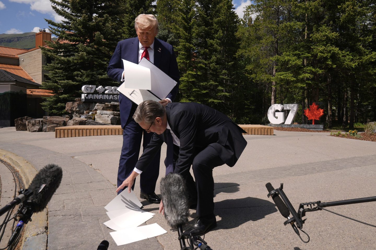 President Donald Trump drops papers as he meets with Britain's Prime Minister Keir Starmer on the sidelines of the G7 Summit, on June 16, 2025, in Kananaskis, Canada.