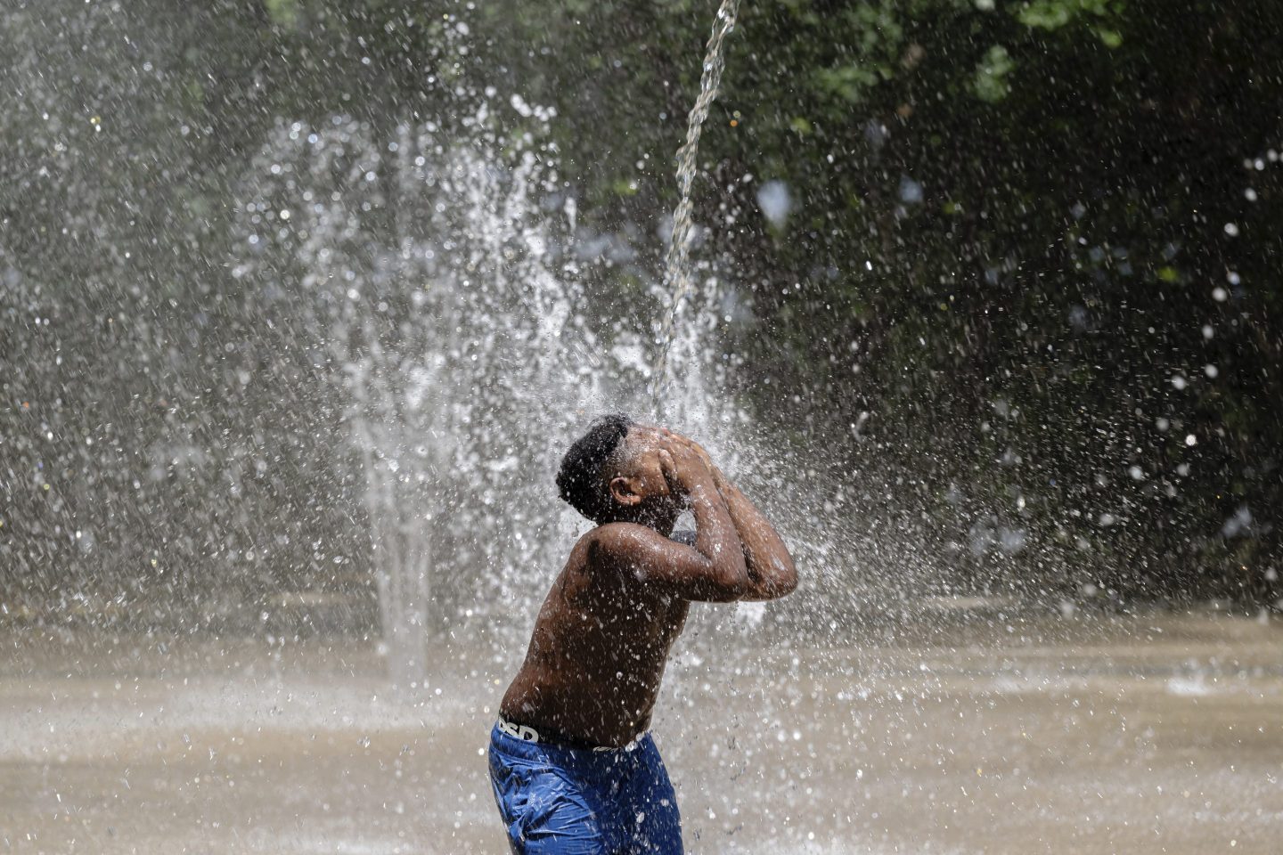 A child covers his face while a stream of water pours down at Waterfront Park on June 22, 2025, in Louisville, Ky.