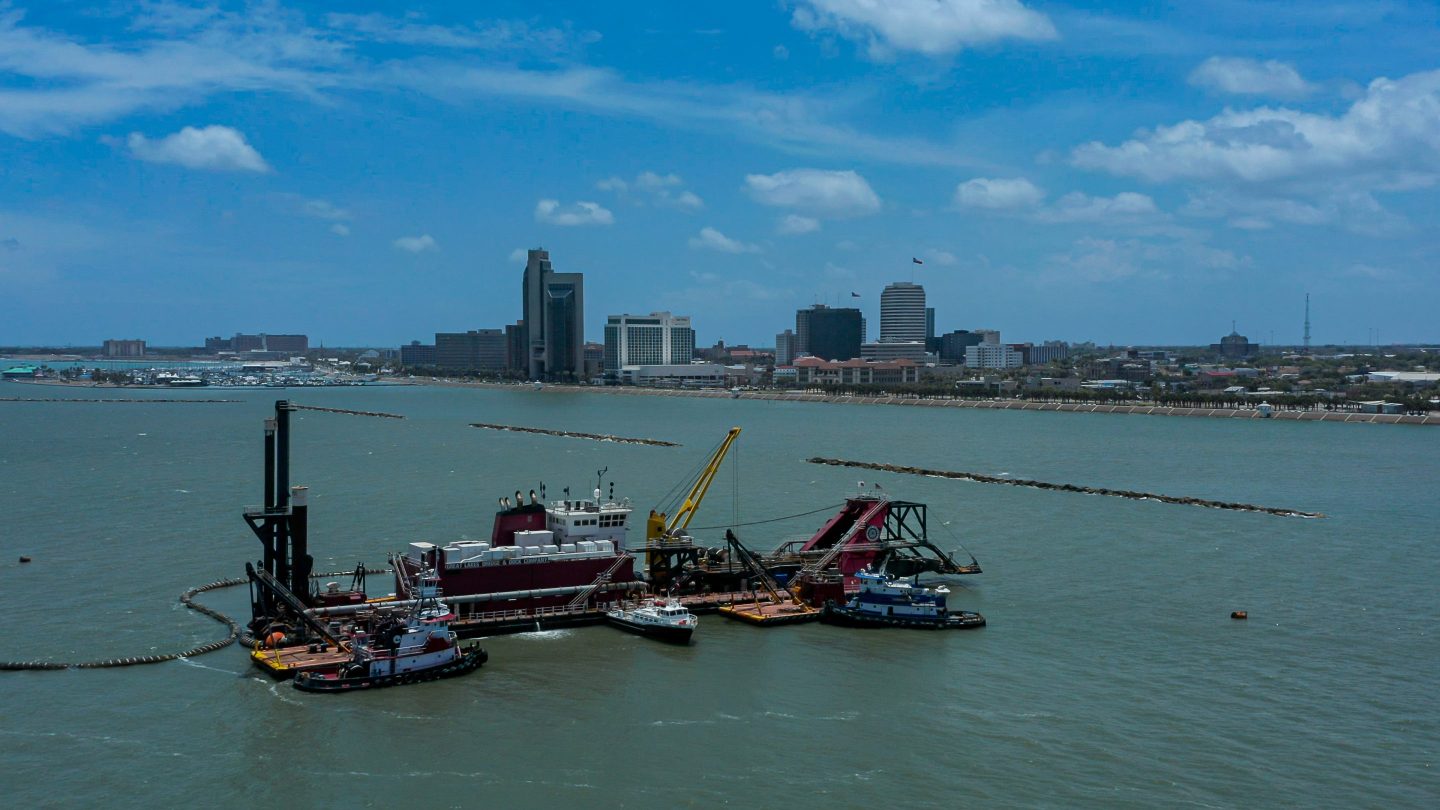 The dredger vessel Ohio works on dredging the Port of Corpus Christi's inner harbor in 2022 with downtown Corpus seen in the background.