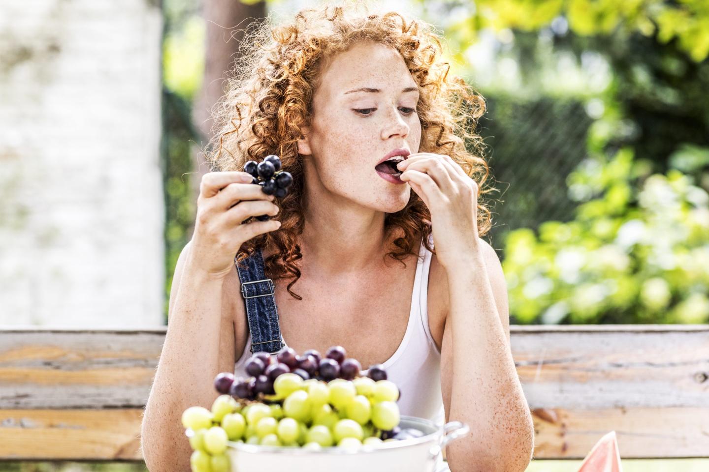 Photo of a young woman eating grapes