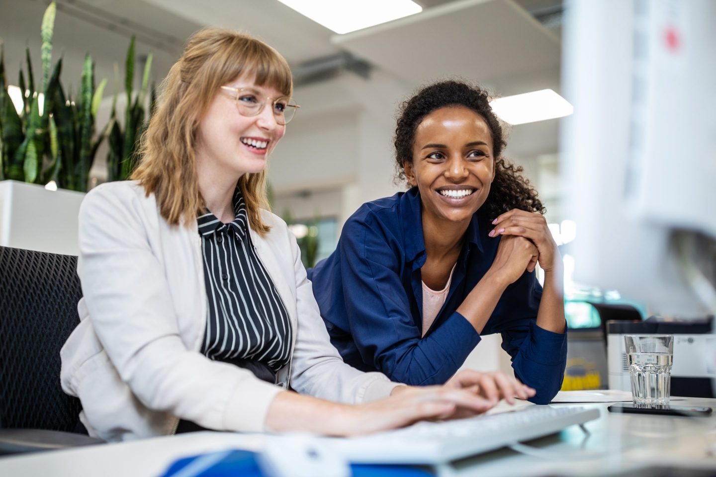 Female executives smiling while looking at computer in office