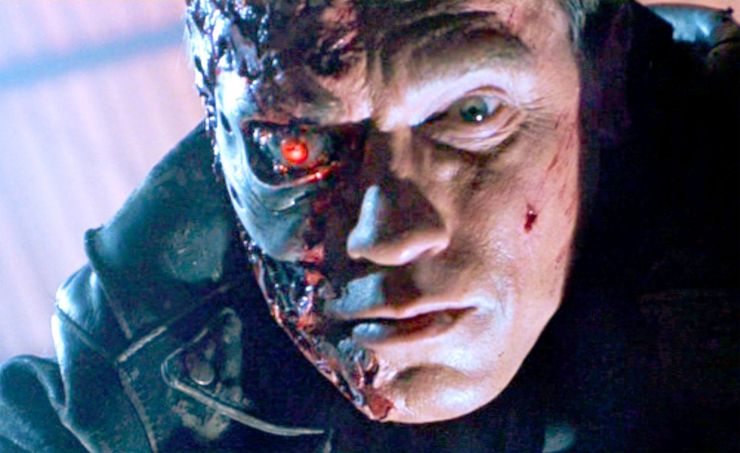 A close-up of the face of Arnold Schwarzenegger as 'The Terminator.' Half of the face reveals the characters identity as a cyborg.