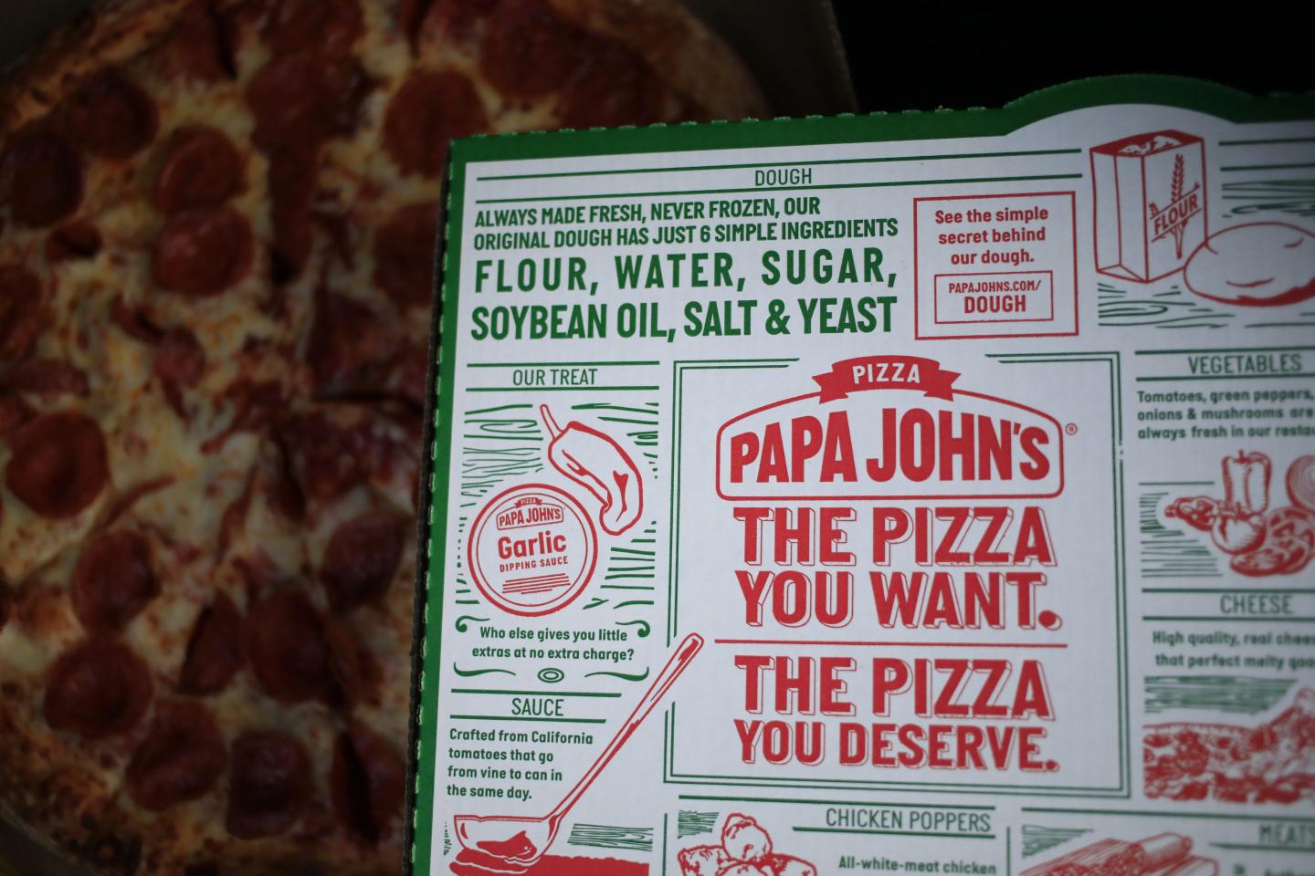 A pizza box in front of a cheese and pepperoni pizza.