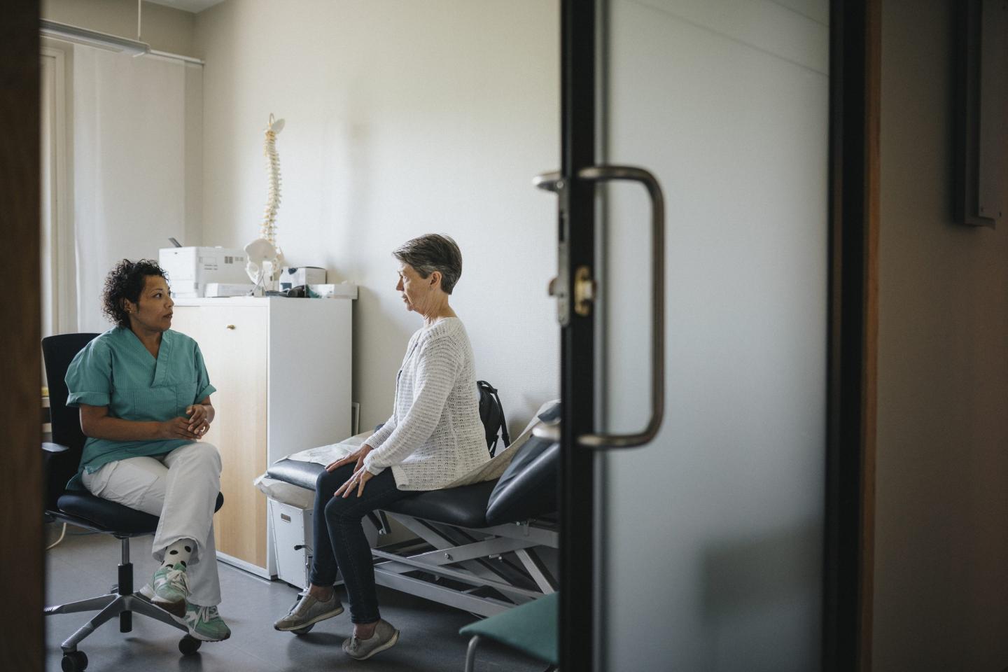 older woman with doctor, model of spine in background