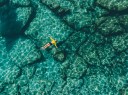 Photo: Woman floating in transparent turquoise sea. Aerial view. - stock photo