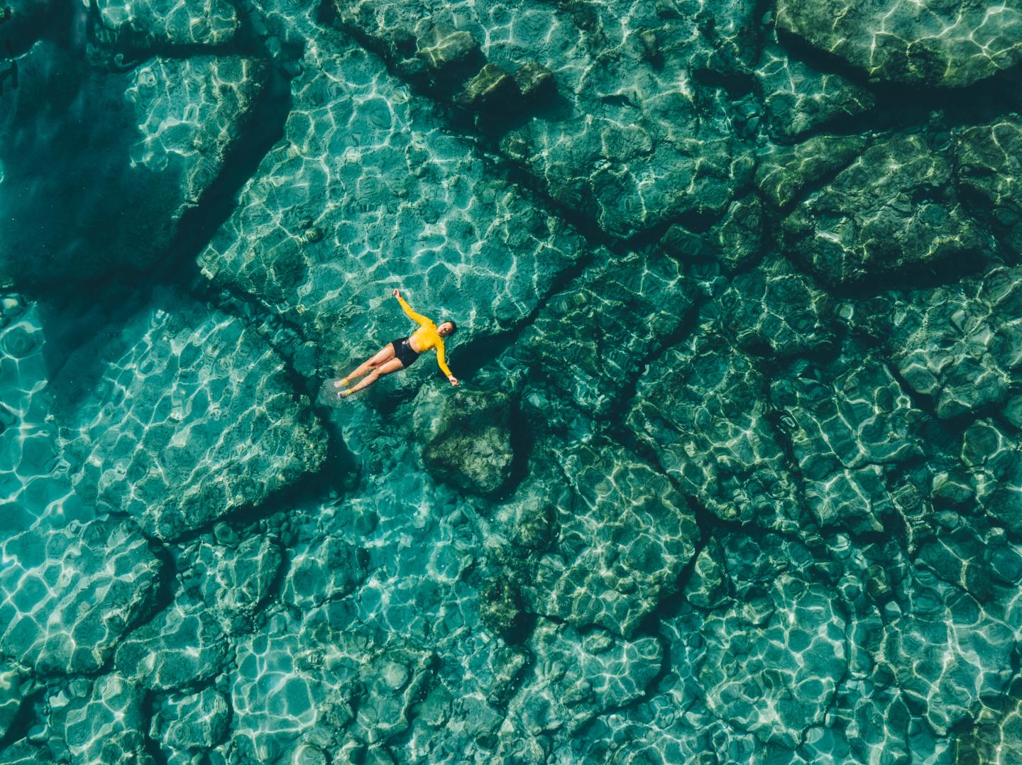 Photo: Woman floating in transparent turquoise sea. Aerial view. - stock photo