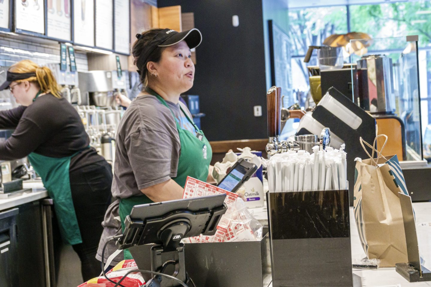 A Starbucks barista stands behind a cash register.