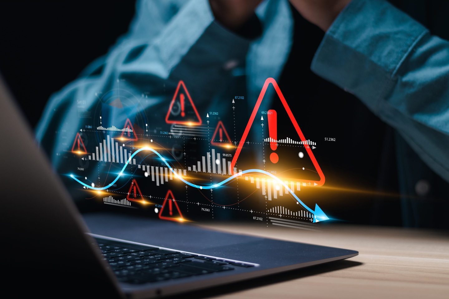 man at laptop computer with hologram of security alert symbols