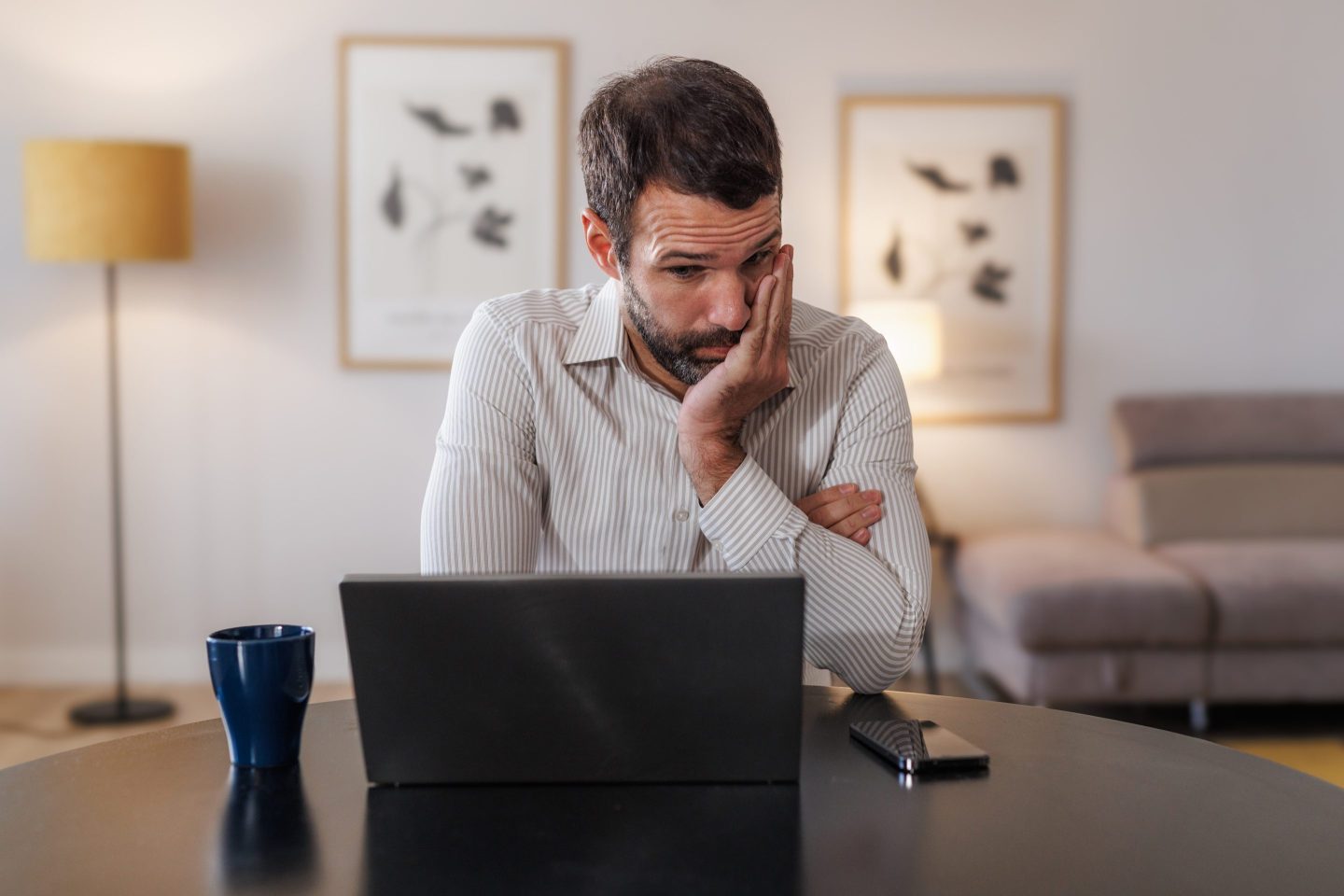 Photo of a man looking at his laptop screen with frustration