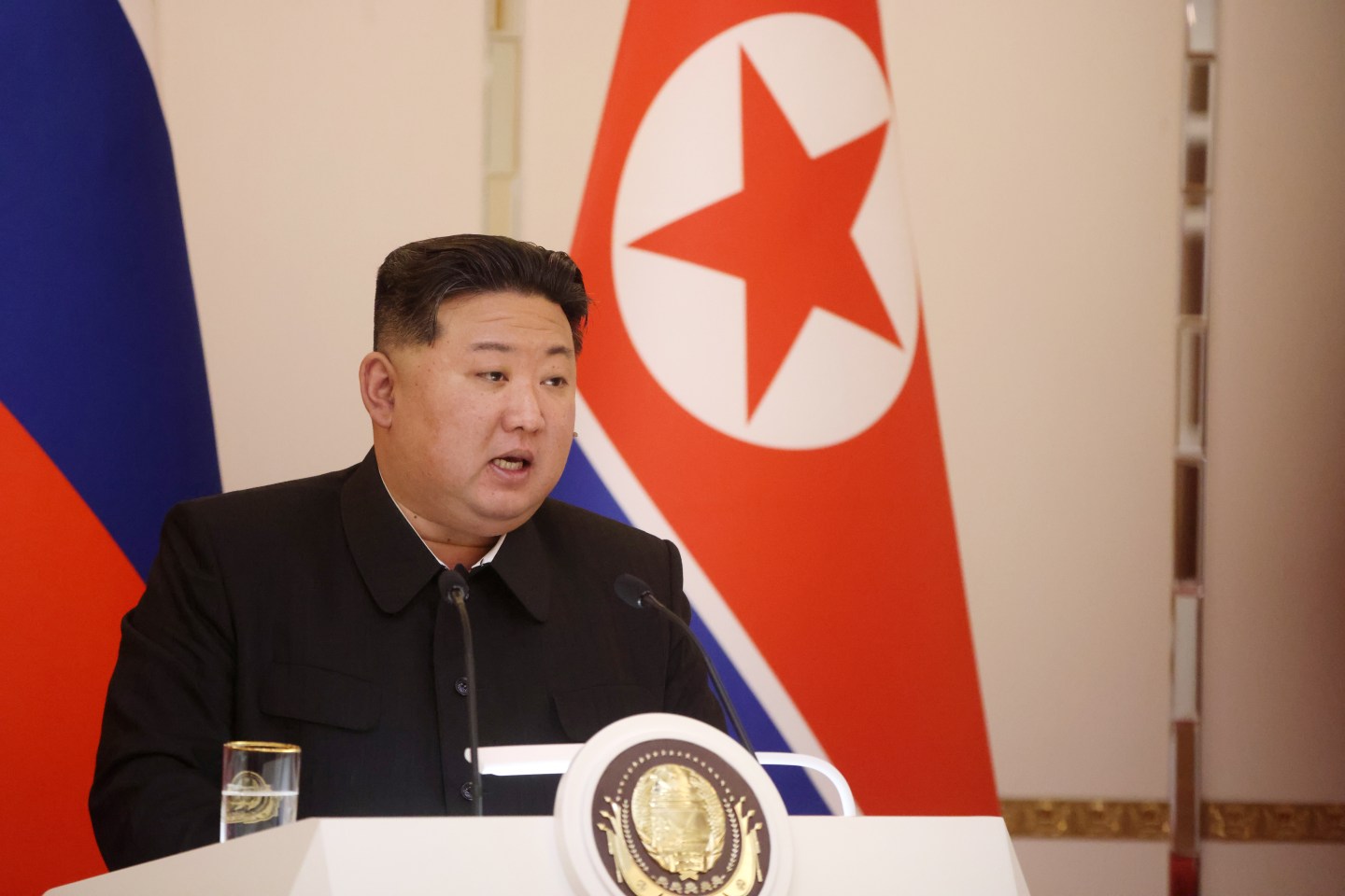 Kim Jong Un speaking into a microphone at a political event.