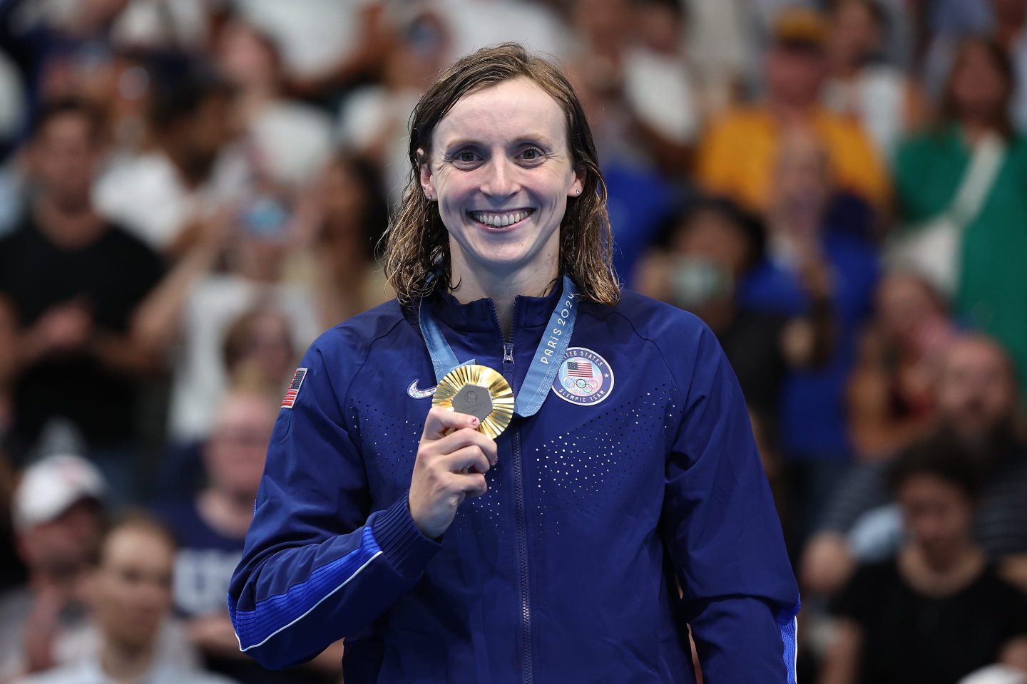 Katie Ledecky holding a gold medal at the Olympic games.